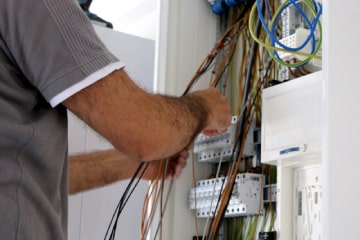 A Man in Grey Checking Wiring in a Unit