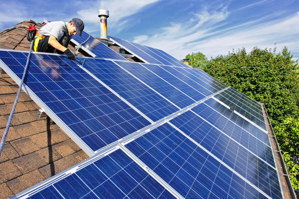 A Man Fixing Solar Panels on the Roof